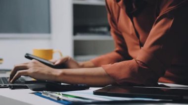 Modern ofiste çalışan genç bir iş adamı. Genç işadamı akıllı telefon kullanıyor ve ofisinde dizüstü bilgisayar kullanıyor..