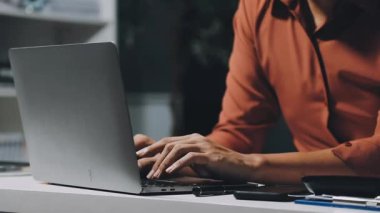 Ofiste dizüstü bilgisayarı ve defteri olan genç bir kadın.