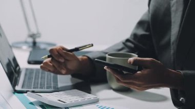Ofiste bilgisayar ve akıllı telefon kullanan bir iş adamı.