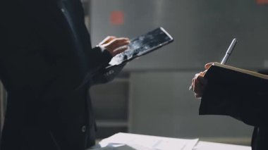 Akıllı telefon tutan ve belgeleri okuyan adama yakın durun.