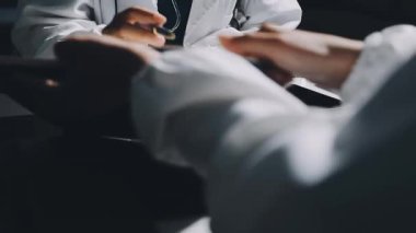 Doktor elinde bir kalem tutuyor ve not alıyor. Doktor muayenehanede notlar alır.