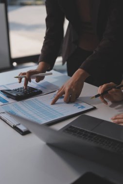 Muhasebe şirketi kazançlı nakit akışı için finansman ve vergilendirme planlaması, ofiste çalışan denetçi ve muhasebeci ekibi, mali verileri ve muhasebe kayıtlarını hesap makinesiyle analiz eder.