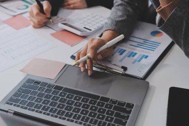 Muhasebe şirketi kazançlı nakit akışı için finansman ve vergilendirme planlaması, ofiste çalışan denetçi ve muhasebeci ekibi, mali verileri ve muhasebe kayıtlarını hesap makinesiyle analiz eder.