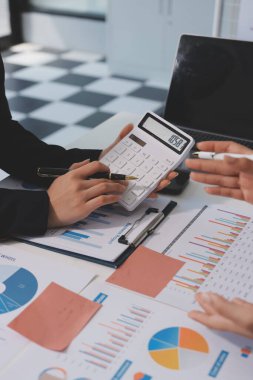 Muhasebe şirketi kazançlı nakit akışı için finansman ve vergilendirme planlaması, ofiste çalışan denetçi ve muhasebeci ekibi, mali verileri ve muhasebe kayıtlarını hesap makinesiyle analiz eder.