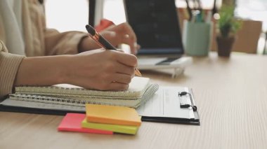 Genç bir kadın deftere yazıyor.