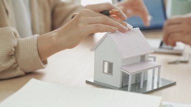 Emlakçı evin anahtarlarını gösteriyor ve ev, sigorta acentesi ya da kredi almak için kontrat imzalıyor.