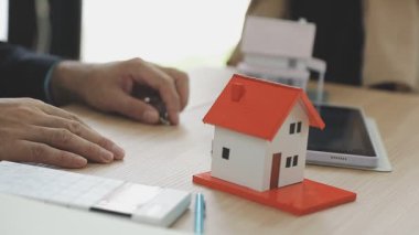 İş adamı ev modelini masada tutuyor.