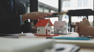 Emlakçı, müşterinin ev modelini kontrattan sonra yeni ev alması için gösteriyor. sigorta ve kredi kavramı.