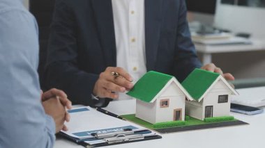 Emlakçının elinde model ev modeli ve model var.