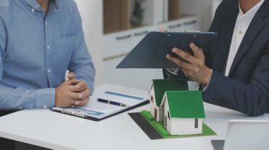 Emlakçı emlak sözleşmesi için ev almak için bir modeli sallıyor.