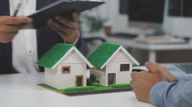 İş adamı elinde model bir ev modeli tutuyor.