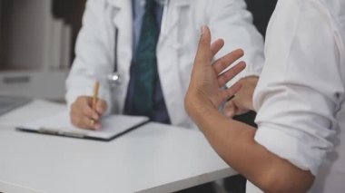 Doktor ve hasta klinikte ya da hastanede masa başında otururken bir şeyler tartışıyorlar.