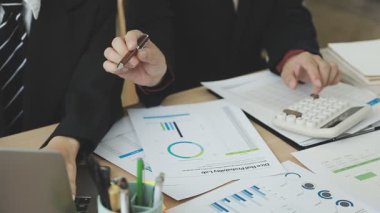 Hesap makineli iş adamı ve kadın masada çalışıyor..