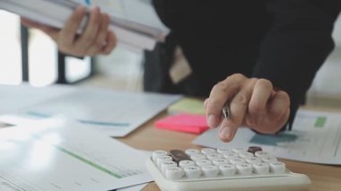 İş adamı eli hesap makinesini tutuyor ve mali belgeyi grafikle hesaplıyor