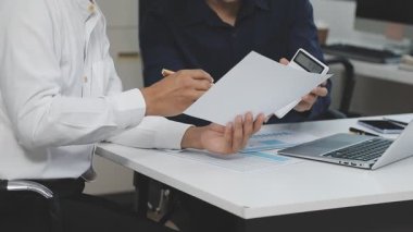 Takım elbiseli genç adam ofisinde bilgisayarla çalışıyor.