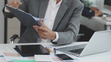 Ofiste dizüstü bilgisayar ve hesap makinesi kullanan iş adamı