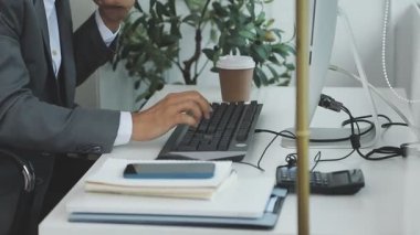 Ofisinde dizüstü bilgisayar ve akıllı telefonla çalışan bir iş adamı.