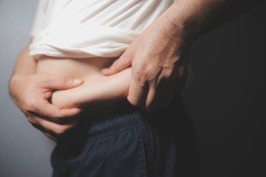 Asyalı şişman bir adam aynanın önünde vücuduna bakıyor. Aşırı göbek yağı, sağlıksız yaşam tarzı, diyet konsepti.