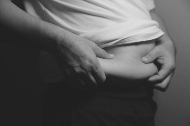 Asyalı şişman bir adam aynanın önünde vücuduna bakıyor. Aşırı göbek yağı, sağlıksız yaşam tarzı, diyet konsepti.