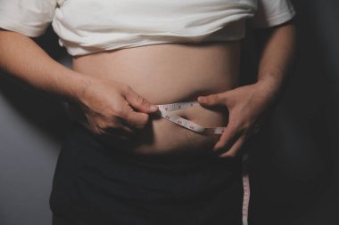 Asyalı şişman bir adam aynanın önünde vücuduna bakıyor. Aşırı göbek yağı, sağlıksız yaşam tarzı, diyet konsepti.