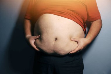 Asyalı şişman bir adam aynanın önünde vücuduna bakıyor. Aşırı göbek yağı, sağlıksız yaşam tarzı, diyet konsepti.