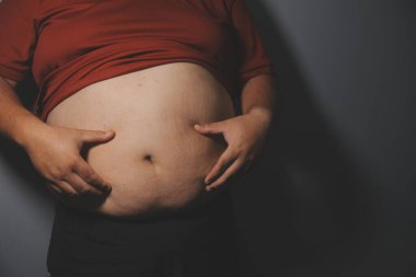 Asyalı şişman bir adam aynanın önünde vücuduna bakıyor. Aşırı göbek yağı, sağlıksız yaşam tarzı, diyet konsepti.