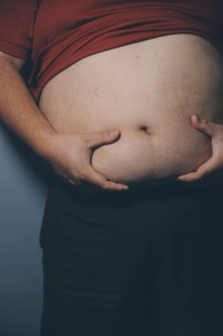 Asyalı şişman bir adam aynanın önünde vücuduna bakıyor. Aşırı göbek yağı, sağlıksız yaşam tarzı, diyet konsepti.