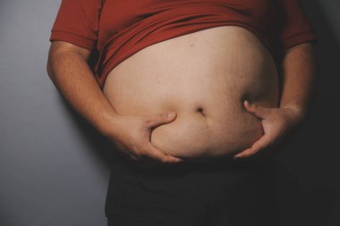 Asyalı şişman bir adam aynanın önünde vücuduna bakıyor. Aşırı göbek yağı, sağlıksız yaşam tarzı, diyet konsepti.