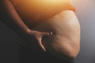 Asyalı şişman bir adam aynanın önünde vücuduna bakıyor. Aşırı göbek yağı, sağlıksız yaşam tarzı, diyet konsepti.