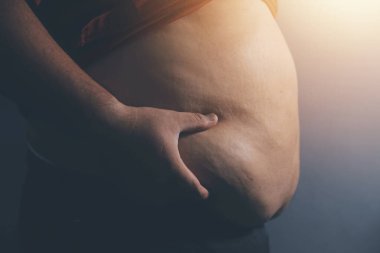 Asyalı şişman bir adam aynanın önünde vücuduna bakıyor. Aşırı göbek yağı, sağlıksız yaşam tarzı, diyet konsepti.