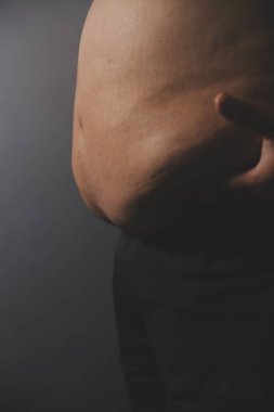 Asyalı şişman bir adam aynanın önünde vücuduna bakıyor. Aşırı göbek yağı, sağlıksız yaşam tarzı, diyet konsepti.