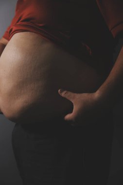 Asyalı şişman bir adam aynanın önünde vücuduna bakıyor. Aşırı göbek yağı, sağlıksız yaşam tarzı, diyet konsepti.