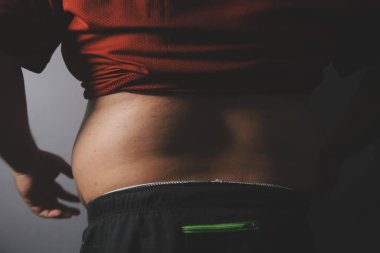 Asyalı şişman bir adam aynanın önünde vücuduna bakıyor. Aşırı göbek yağı, sağlıksız yaşam tarzı, diyet konsepti.