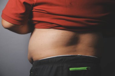 Asyalı şişman bir adam aynanın önünde vücuduna bakıyor. Aşırı göbek yağı, sağlıksız yaşam tarzı, diyet konsepti.