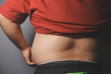 Asyalı şişman bir adam aynanın önünde vücuduna bakıyor. Aşırı göbek yağı, sağlıksız yaşam tarzı, diyet konsepti.