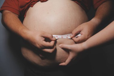 Asyalı şişman bir adam aynanın önünde vücuduna bakıyor. Aşırı göbek yağı, sağlıksız yaşam tarzı, diyet konsepti.