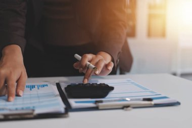 Muhasebe şirketi kazançlı nakit akışı için finansman ve vergilendirme planlaması, ofiste çalışan denetçi ve muhasebeci ekibi, mali verileri ve muhasebe kayıtlarını hesap makinesiyle analiz eder.