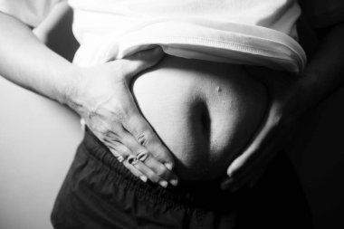 Asyalı şişman bir adam aynanın önünde vücuduna bakıyor. Aşırı göbek yağı, sağlıksız yaşam tarzı, diyet konsepti.