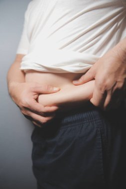 Asyalı şişman bir adam aynanın önünde vücuduna bakıyor. Aşırı göbek yağı, sağlıksız yaşam tarzı, diyet konsepti.