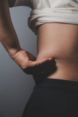 Asyalı şişman bir adam aynanın önünde vücuduna bakıyor. Aşırı göbek yağı, sağlıksız yaşam tarzı, diyet konsepti.