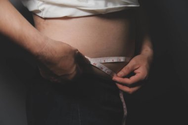 Asyalı şişman bir adam aynanın önünde vücuduna bakıyor. Aşırı göbek yağı, sağlıksız yaşam tarzı, diyet konsepti.