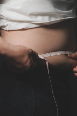 Asyalı şişman bir adam aynanın önünde vücuduna bakıyor. Aşırı göbek yağı, sağlıksız yaşam tarzı, diyet konsepti.