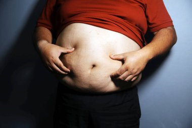 Asyalı şişman bir adam aynanın önünde vücuduna bakıyor. Aşırı göbek yağı, sağlıksız yaşam tarzı, diyet konsepti.