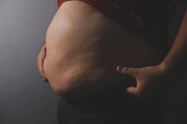 Asyalı şişman bir adam aynanın önünde vücuduna bakıyor. Aşırı göbek yağı, sağlıksız yaşam tarzı, diyet konsepti.