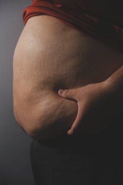 Asyalı şişman bir adam aynanın önünde vücuduna bakıyor. Aşırı göbek yağı, sağlıksız yaşam tarzı, diyet konsepti.