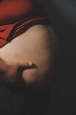 Asyalı şişman bir adam aynanın önünde vücuduna bakıyor. Aşırı göbek yağı, sağlıksız yaşam tarzı, diyet konsepti.