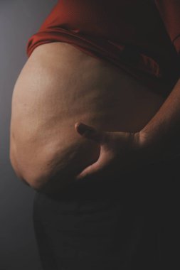 Asyalı şişman bir adam aynanın önünde vücuduna bakıyor. Aşırı göbek yağı, sağlıksız yaşam tarzı, diyet konsepti.