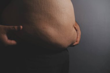 Asyalı şişman bir adam aynanın önünde vücuduna bakıyor. Aşırı göbek yağı, sağlıksız yaşam tarzı, diyet konsepti.