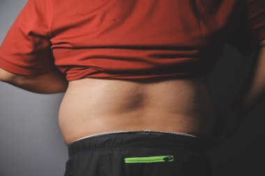 Asyalı şişman bir adam aynanın önünde vücuduna bakıyor. Aşırı göbek yağı, sağlıksız yaşam tarzı, diyet konsepti.