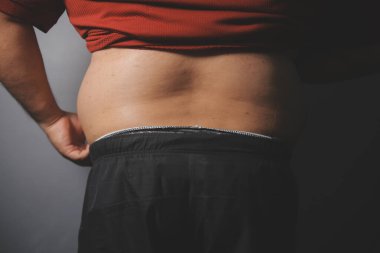 Asyalı şişman bir adam aynanın önünde vücuduna bakıyor. Aşırı göbek yağı, sağlıksız yaşam tarzı, diyet konsepti.